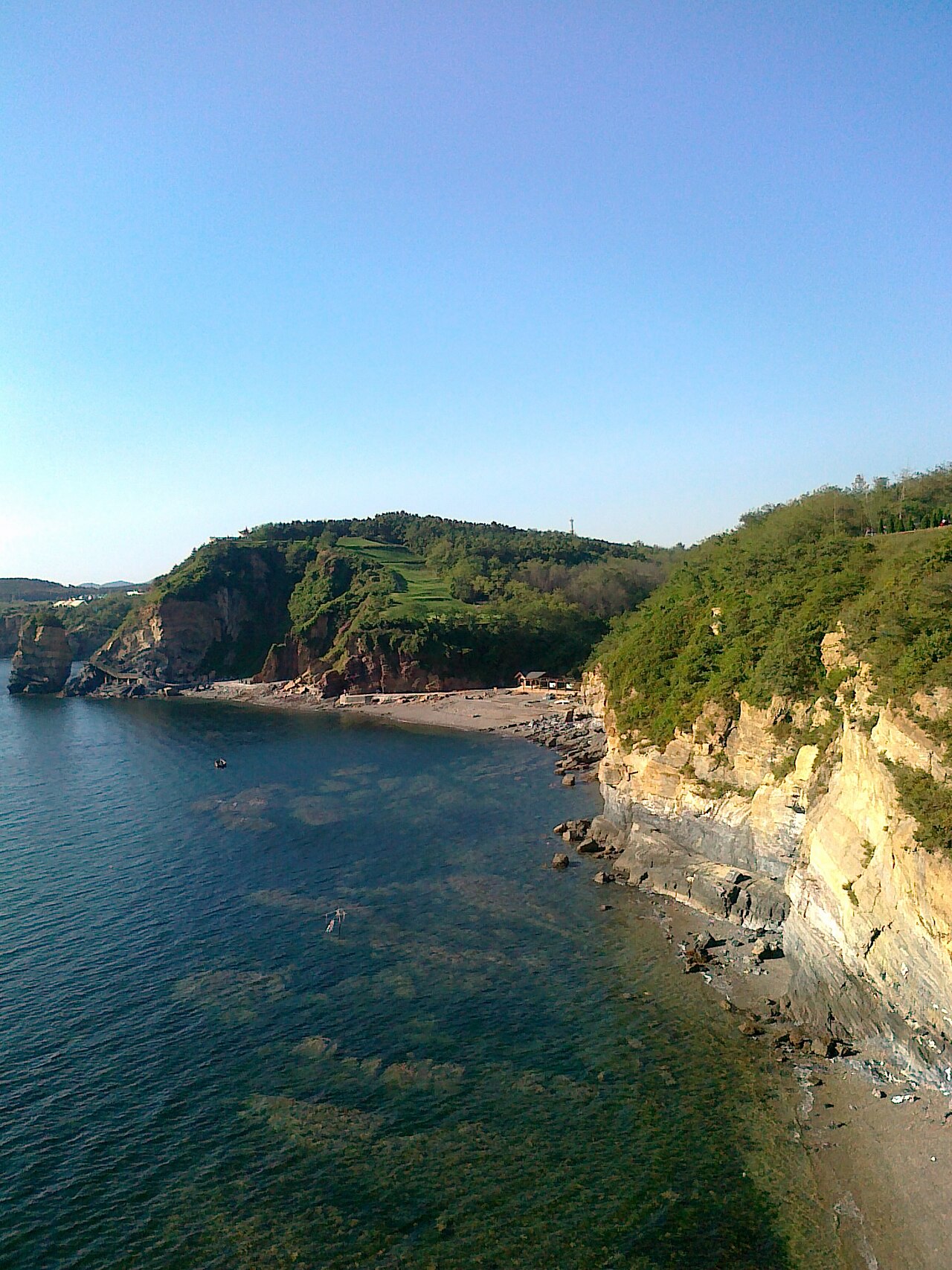 Falaises sculptées par la mer et eaux vertes limpides sur le littoral du géoparc national de Jinshitan.