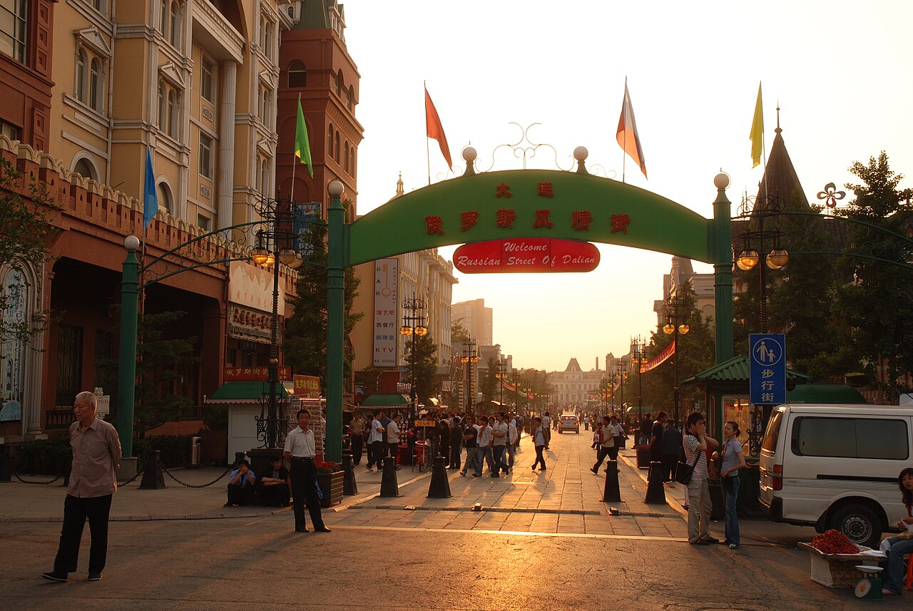 La porte verte de la rue russe de Dalian baignée par la lumière de fin d’après-midi, au-dessus de l’allée piétonne.