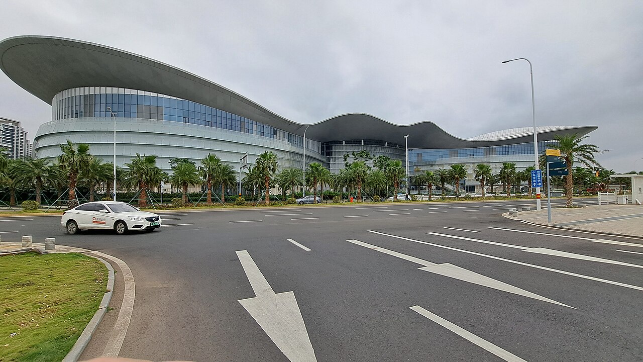 หลังคาทรงคลื่นขนาดใหญ่ของ Haikou International Duty-Free City ทอดตัวอยู่เหนือถนนทางเข้า
