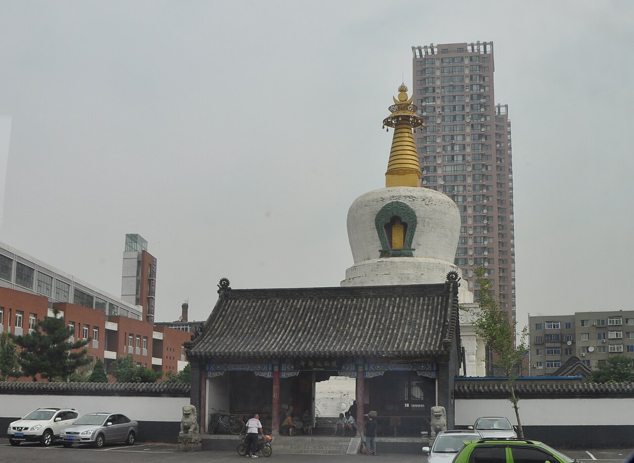 Die weiße buddhistische Stupa der West-Pagode ragt über den Straßen von Xita empor, dahinter stehen Wohnhochhäuser.