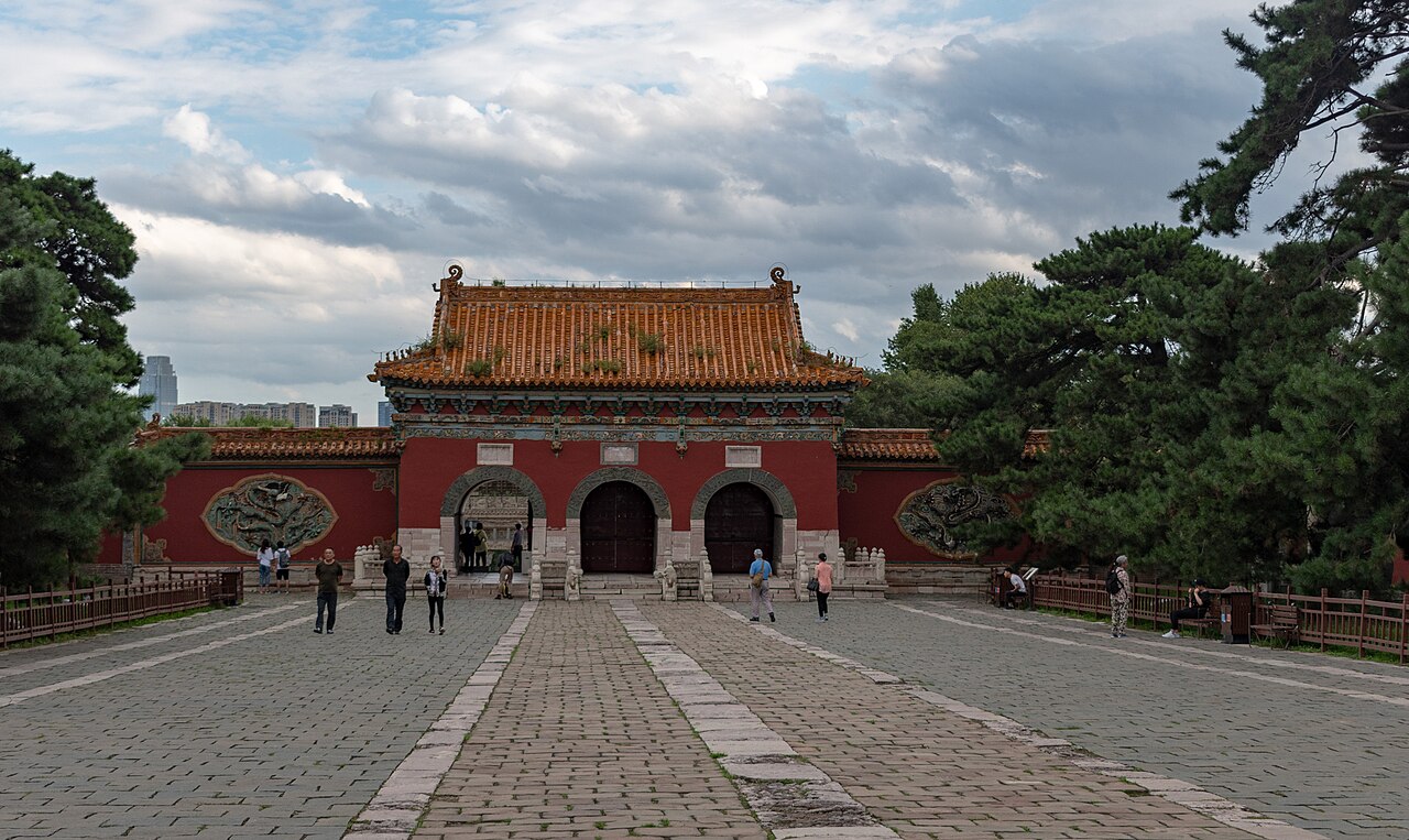Das rote Zeremonientor des Zhao-Mausoleums zwischen jahrhundertealten Kiefern im Beiling-Park.