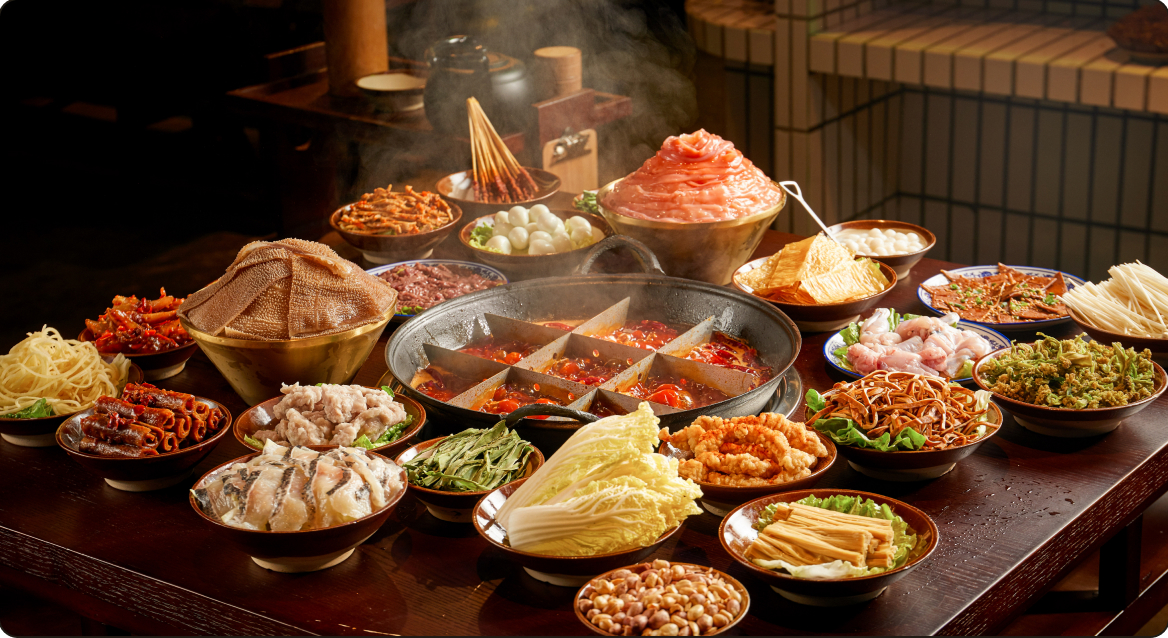 A hotpot spread on a dark wooden table, ringed by small dishes