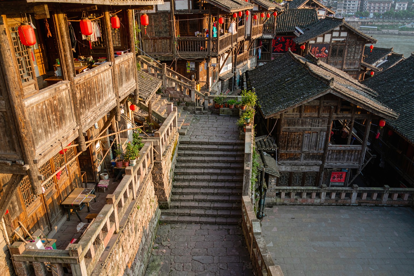 老重庆街区里，陡峭石阶穿过挂着红灯笼的斑驳木质吊脚楼向下延伸