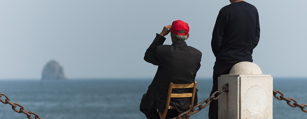 Locals on the seaside promenade of Xinghai Bay with a small islet offshore