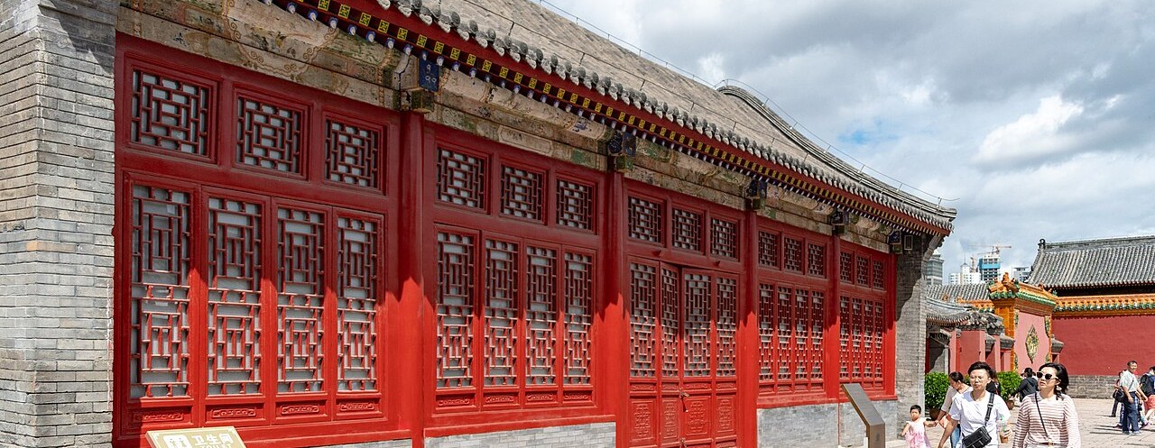 The red-lacquered courtyard wall of the Mukden Palace with visitors strolling past